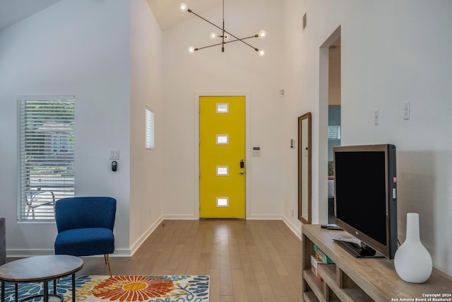 foyer featuring hardwood / wood-style flooring, a notable chandelier, and high vaulted ceiling