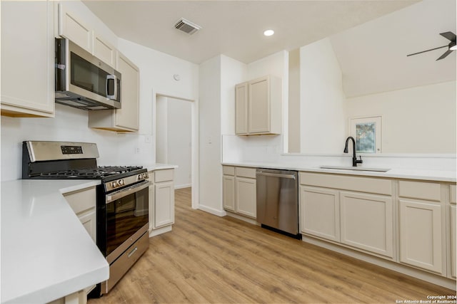 kitchen with ceiling fan, sink, stainless steel appliances, and light hardwood / wood-style flooring