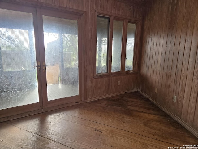 entryway featuring french doors, a wealth of natural light, hardwood / wood-style floors, and wood walls