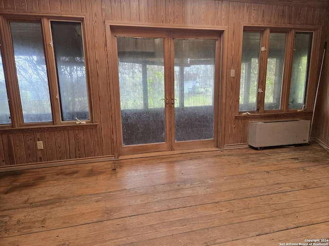 entryway with wood-type flooring, radiator heating unit, and wood walls