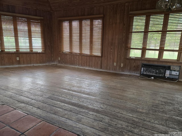 empty room with wood-type flooring, wooden walls, and an AC wall unit