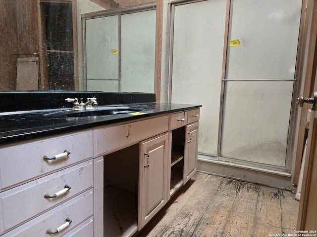 bathroom with wood-type flooring, vanity, and walk in shower