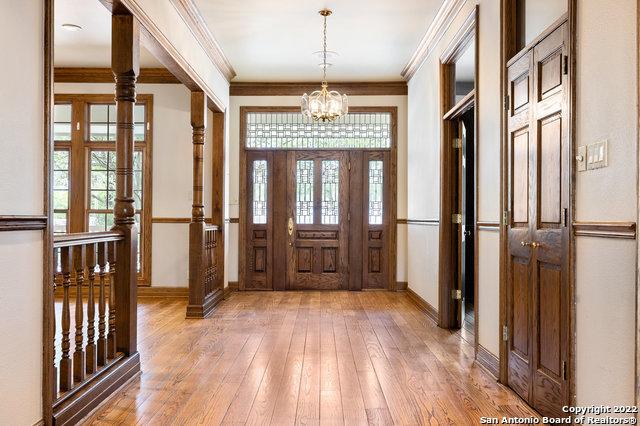 entrance foyer with hardwood / wood-style floors, ornamental molding, and a chandelier