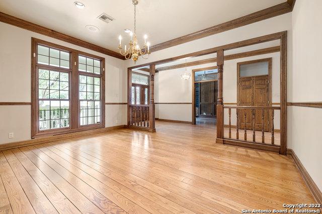 spare room featuring light wood-type flooring, crown molding, and a chandelier