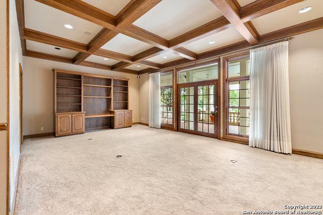 unfurnished living room featuring light carpet, beamed ceiling, and coffered ceiling