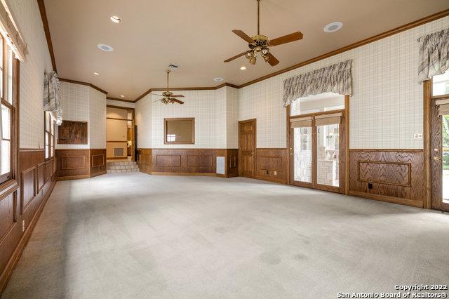 unfurnished living room with crown molding, ceiling fan, and light colored carpet