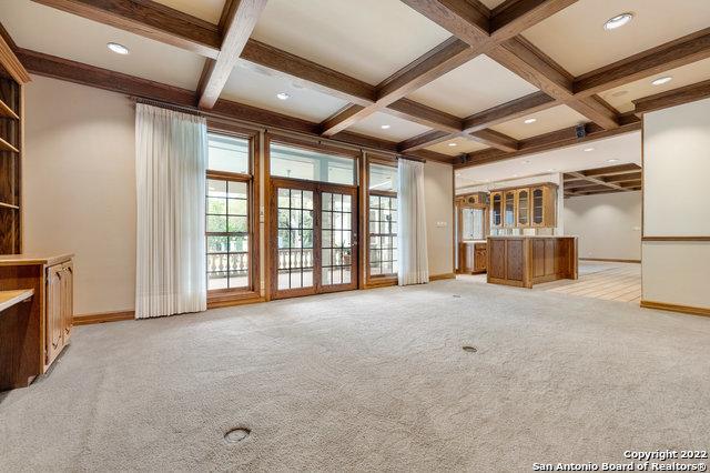 unfurnished living room with light carpet, beamed ceiling, and coffered ceiling