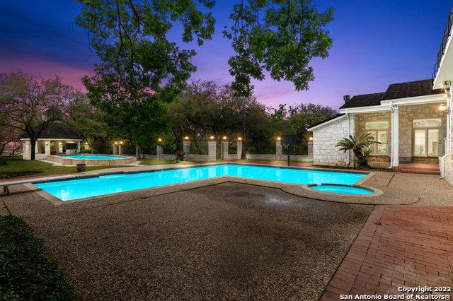 pool at dusk featuring an in ground hot tub and a patio area