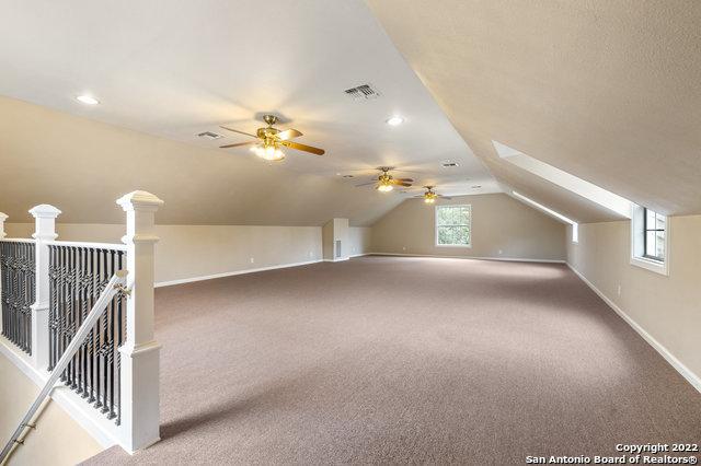 additional living space featuring carpet, ceiling fan, and lofted ceiling with skylight