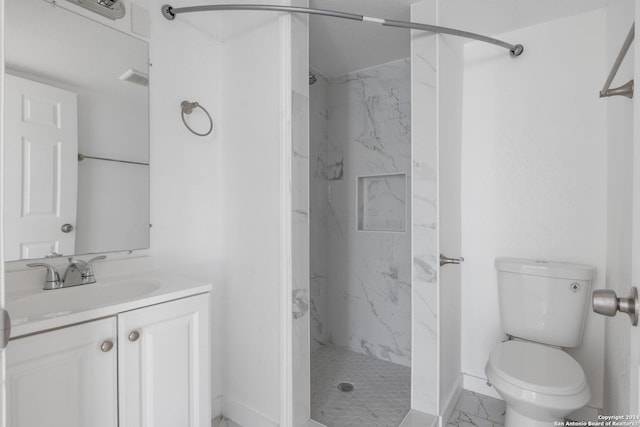 bathroom with vanity, toilet, and a tile shower