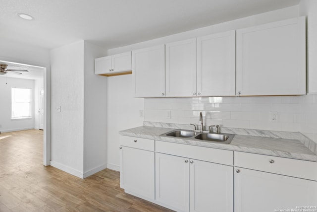 kitchen with backsplash, white cabinets, sink, light hardwood / wood-style flooring, and ceiling fan