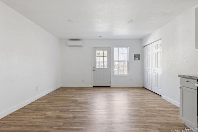 spare room featuring a textured ceiling, light hardwood / wood-style floors, and a wall mounted AC