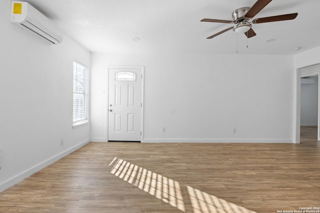 empty room featuring an AC wall unit, ceiling fan, and light hardwood / wood-style floors