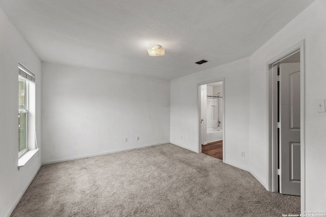 spare room with dark carpet and a textured ceiling