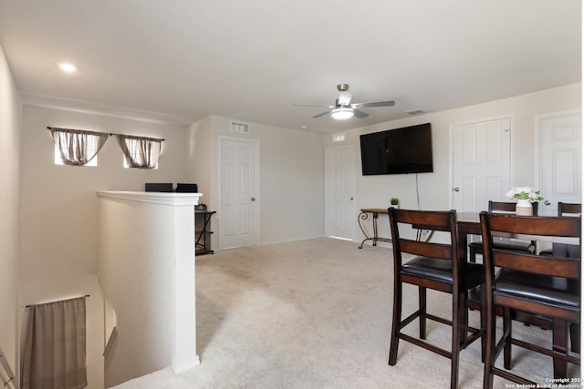 carpeted dining space with ceiling fan