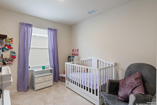 bedroom featuring light carpet and a nursery area