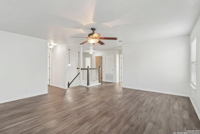 unfurnished living room featuring a textured ceiling, ceiling fan, and dark wood-type flooring