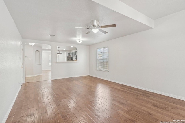 spare room featuring wood-type flooring and ceiling fan with notable chandelier