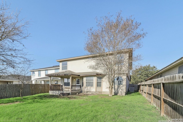 rear view of property featuring a yard and covered porch