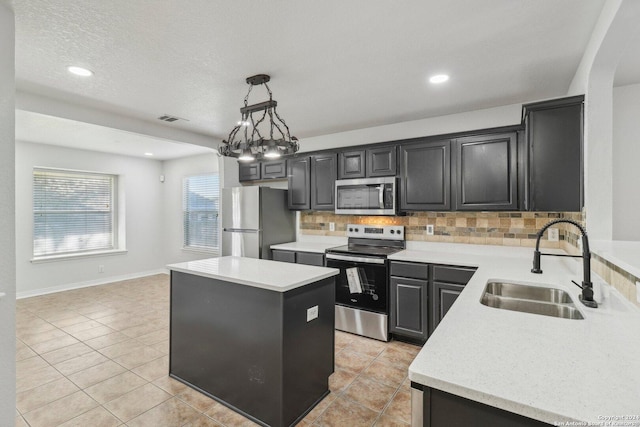 kitchen featuring decorative backsplash, appliances with stainless steel finishes, sink, a kitchen island, and hanging light fixtures