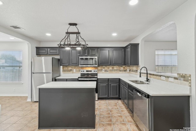 kitchen featuring sink, hanging light fixtures, decorative backsplash, light tile patterned floors, and appliances with stainless steel finishes