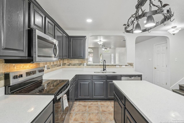 kitchen with ceiling fan, sink, stainless steel appliances, decorative backsplash, and light tile patterned flooring