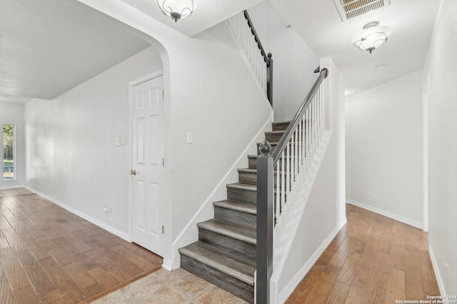 staircase featuring hardwood / wood-style floors and a textured ceiling