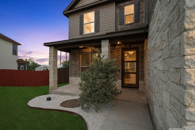 exterior entry at dusk featuring a yard