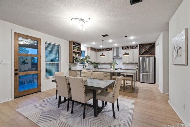 dining room with a textured ceiling and light hardwood / wood-style flooring