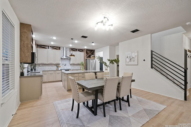 dining space featuring light hardwood / wood-style flooring, an inviting chandelier, a textured ceiling, and sink