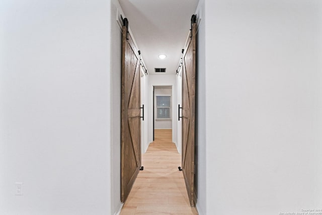 hallway with a barn door and light hardwood / wood-style flooring