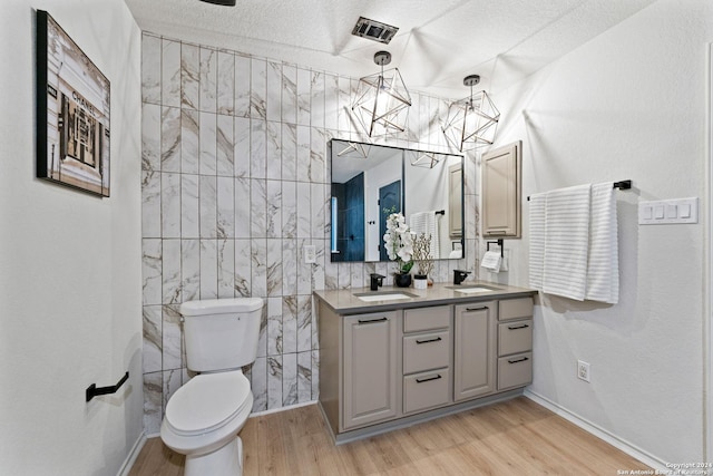 bathroom with vanity, a textured ceiling, hardwood / wood-style flooring, and tile walls