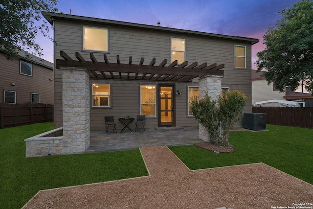 back house at dusk featuring a pergola, a patio area, a yard, and central air condition unit