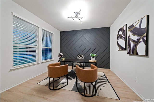 living area featuring a chandelier, a textured ceiling, and light wood-type flooring