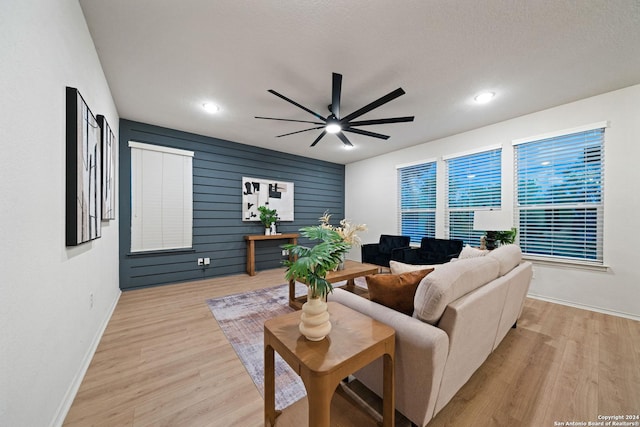 living room featuring a textured ceiling, light wood-type flooring, and ceiling fan