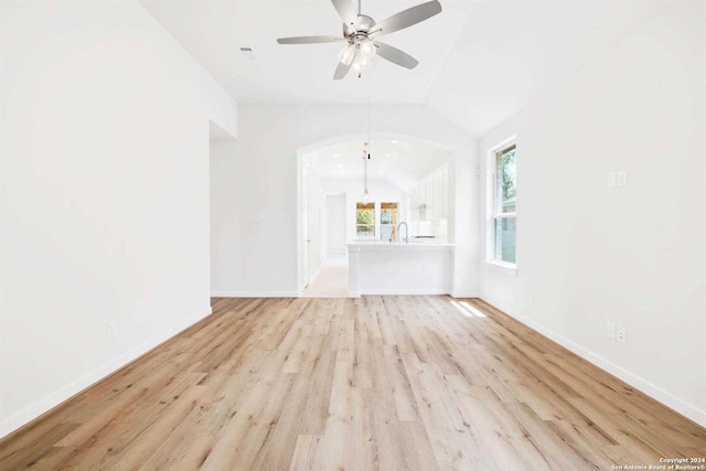 unfurnished living room with lofted ceiling, ceiling fan, light wood-type flooring, and sink