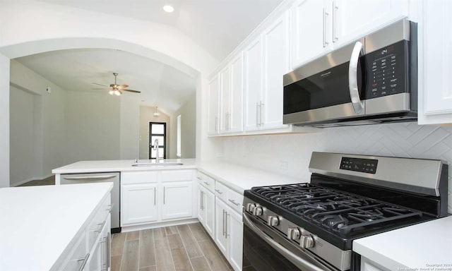 kitchen featuring sink, white cabinetry, stainless steel appliances, and vaulted ceiling