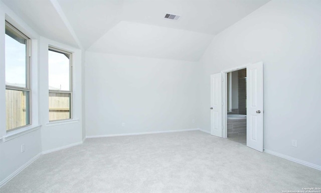 carpeted spare room featuring plenty of natural light and vaulted ceiling