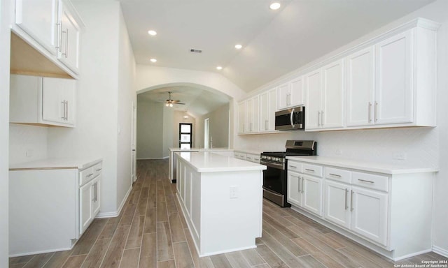 kitchen featuring stainless steel appliances, vaulted ceiling, light hardwood / wood-style flooring, white cabinets, and a center island