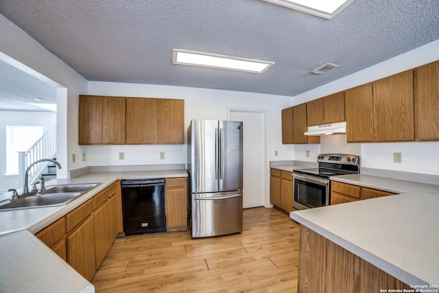 kitchen featuring appliances with stainless steel finishes, a textured ceiling, light hardwood / wood-style floors, and sink