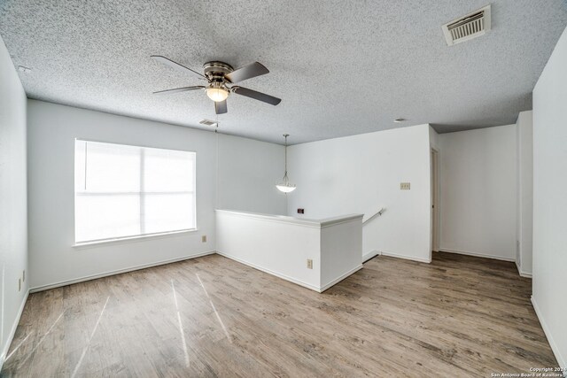 empty room featuring ceiling fan, wood-type flooring, and a textured ceiling