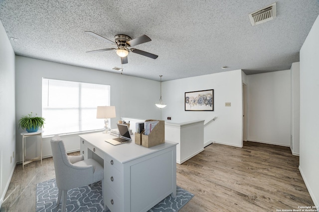 office with a textured ceiling, light hardwood / wood-style floors, and ceiling fan