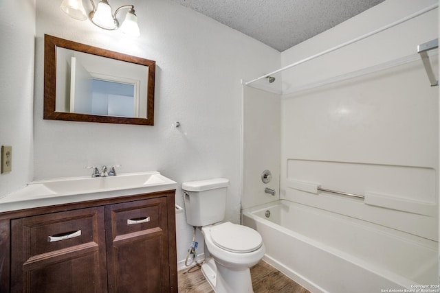 full bathroom featuring shower / bathing tub combination, hardwood / wood-style floors, a textured ceiling, toilet, and vanity