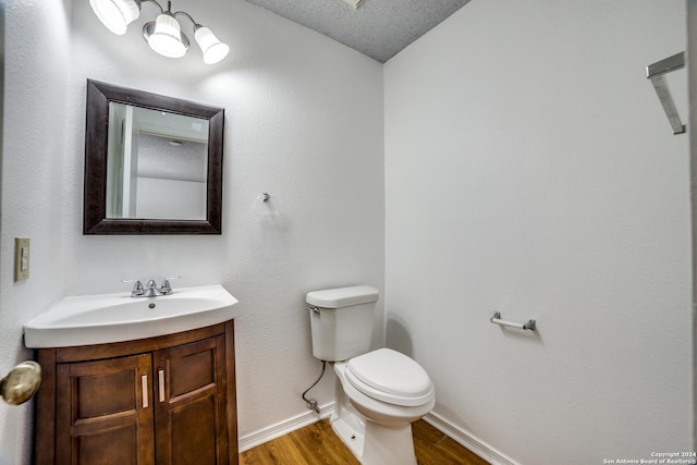 bathroom with vanity, wood-type flooring, a textured ceiling, and toilet