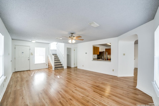 unfurnished living room featuring ceiling fan, light hardwood / wood-style flooring, and a textured ceiling