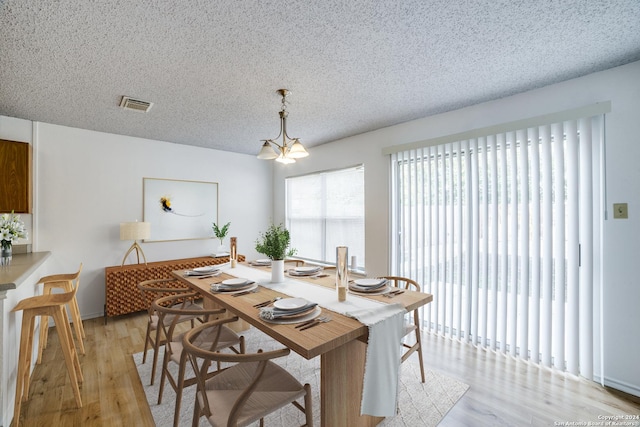 dining room with a notable chandelier, a textured ceiling, and light hardwood / wood-style flooring