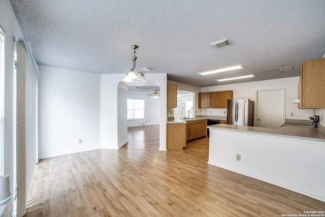 kitchen with stove, light hardwood / wood-style flooring, stainless steel fridge, a textured ceiling, and kitchen peninsula