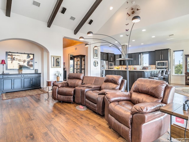 living room with beam ceiling, wood-type flooring, and high vaulted ceiling