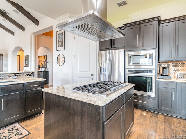 kitchen featuring light stone countertops, a center island, tasteful backsplash, island exhaust hood, and appliances with stainless steel finishes