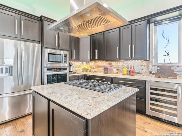 kitchen with light stone countertops, beverage cooler, stainless steel appliances, island exhaust hood, and a kitchen island